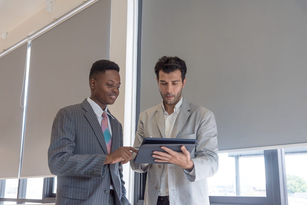 Boss teaching African subordinates with care by tablet